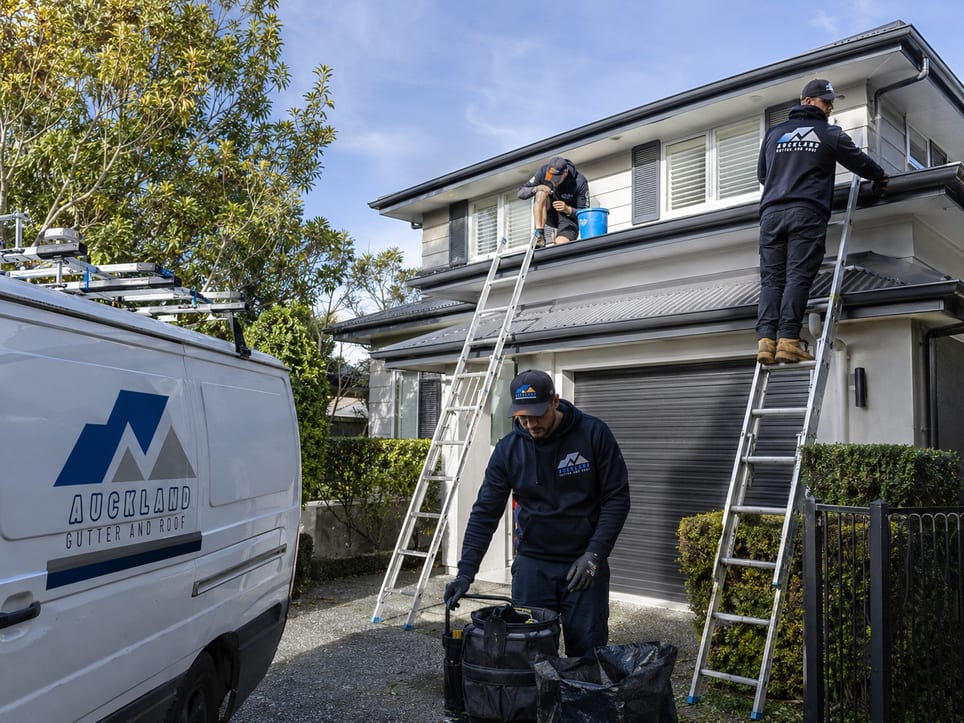 Auckland Gutter and Roof crew on ladders clearing gutters on a two-storey Auckland home